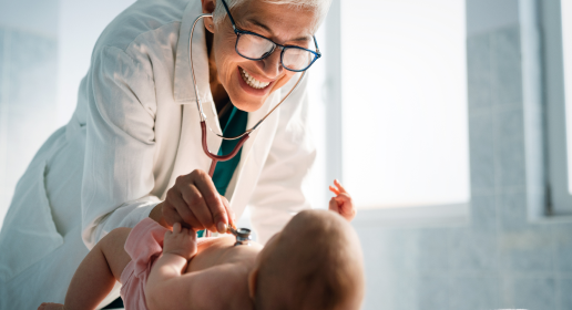eine Ärztinh untersucht ein Baby mit dem Stetoskop und schaut ob es gesund ist